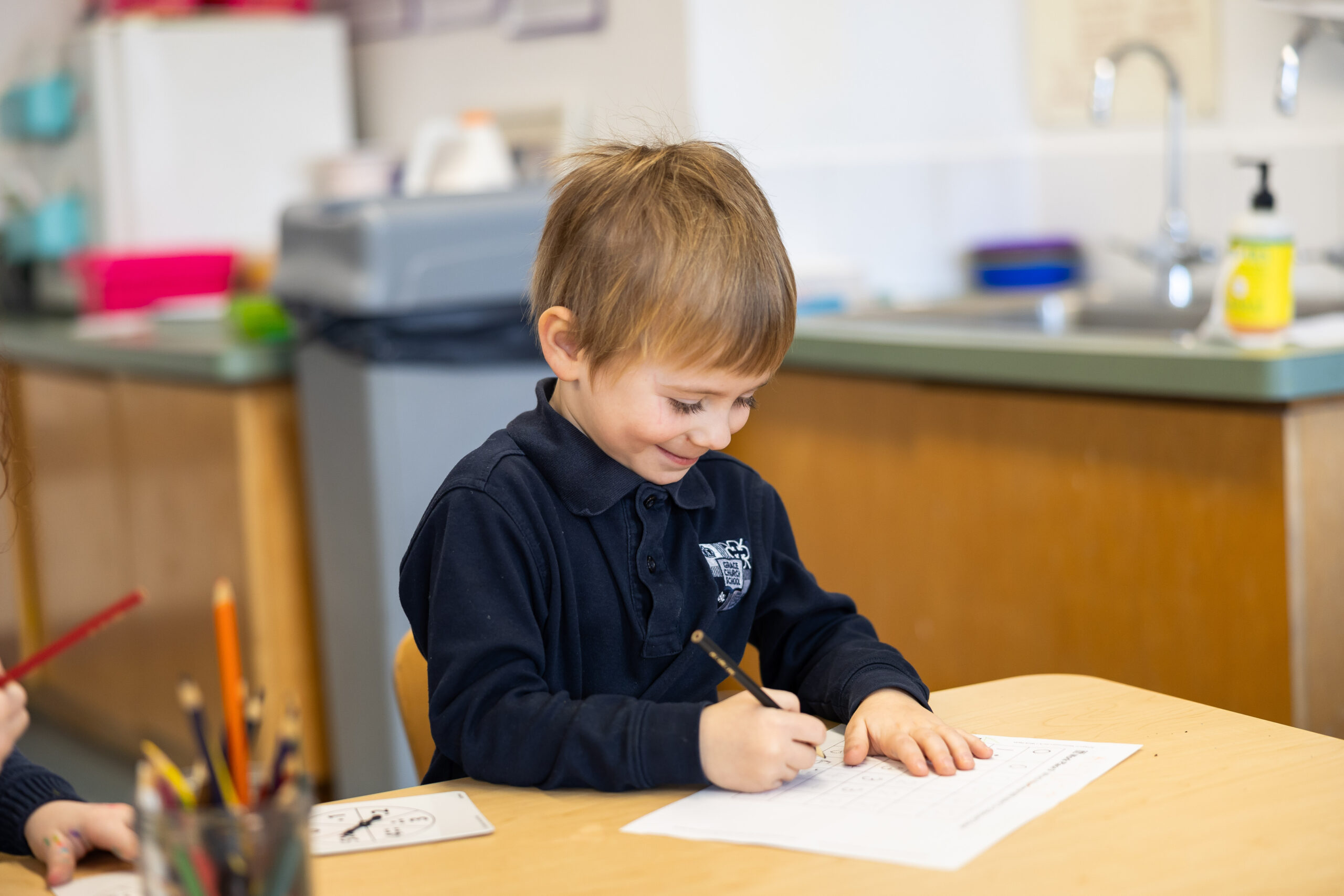 Early childhood student writing at desk.