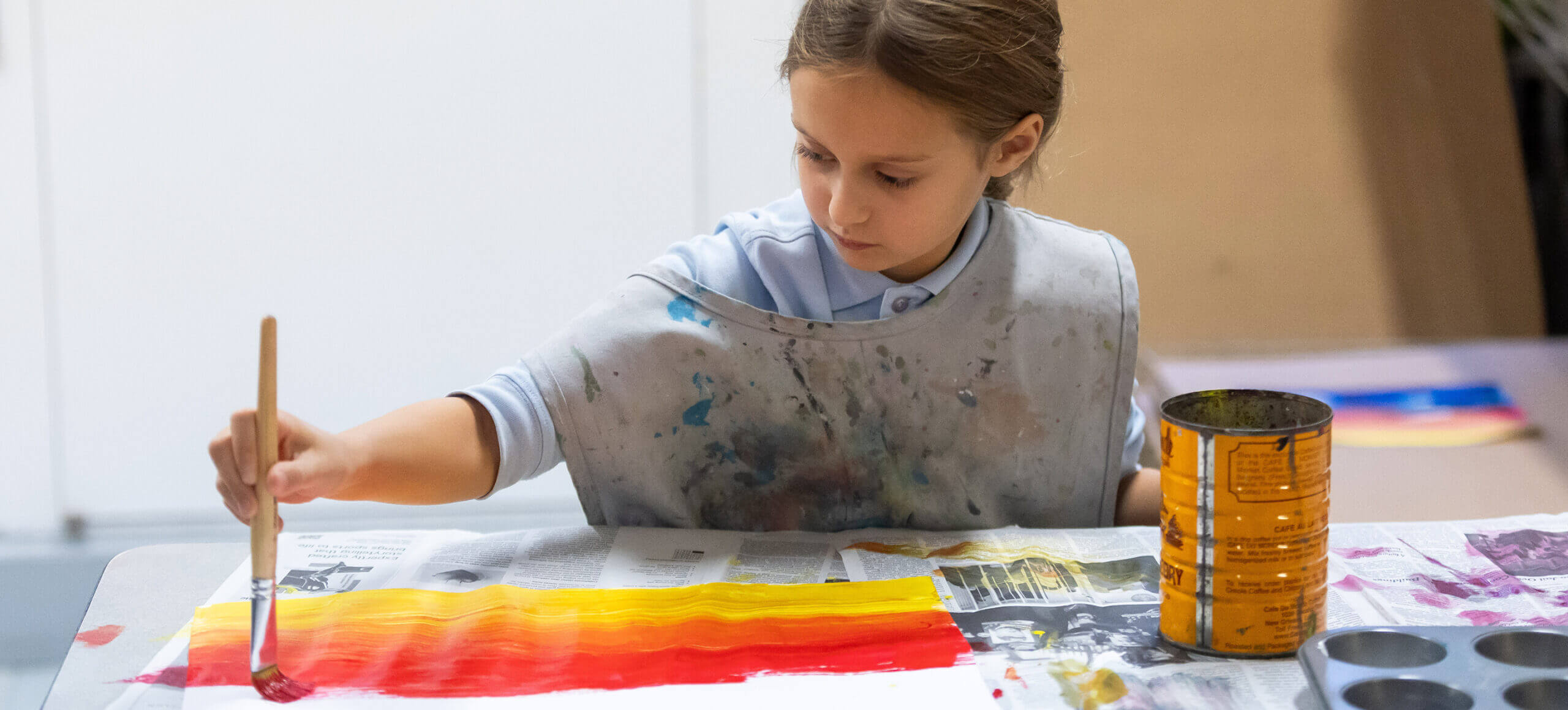 A young female student is painting gin vibrant colors on paper